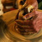 Close-up of hands shaping clay on a pottery wheel, highlighting the art of ceramics.