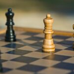 Detailed view of chess pieces on a classic wooden chessboard outdoors.