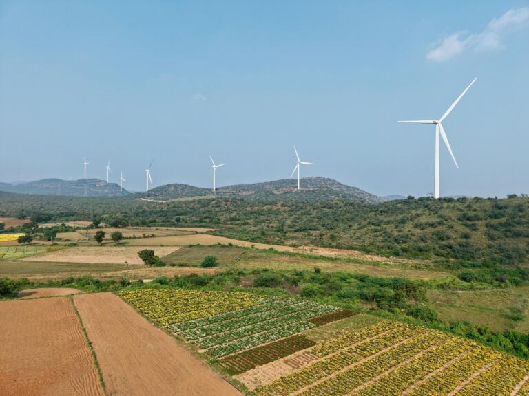 Aerial view of wind turbines in a lush rural landscape under clear blue skies.